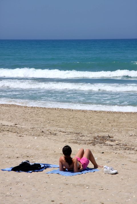 A girl sunabathing on a sandy beach